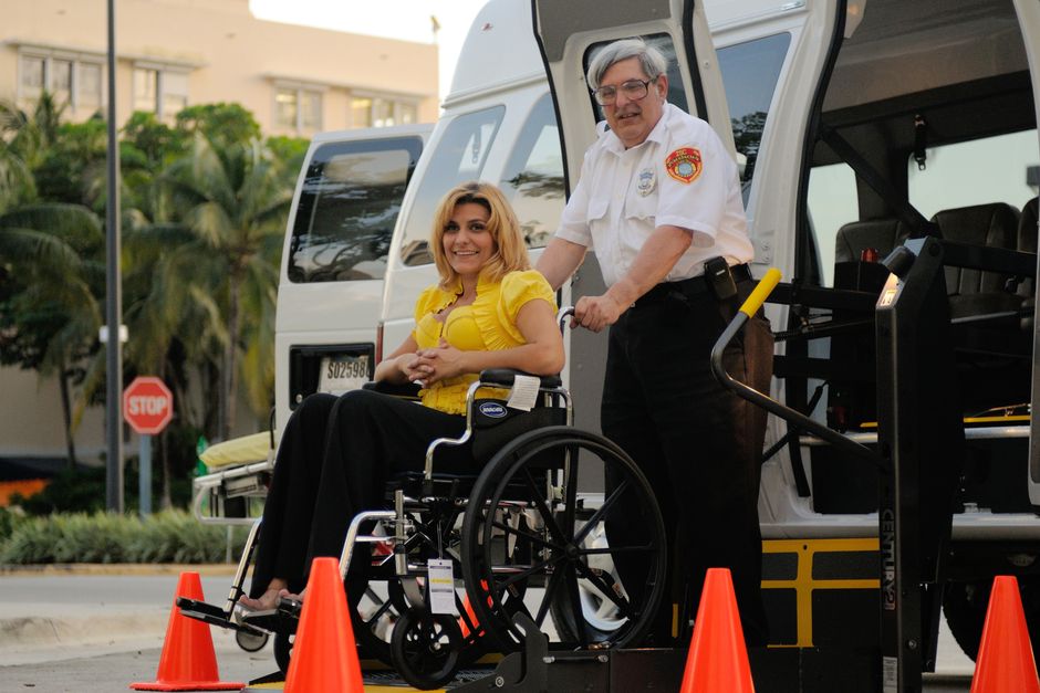 A transport service assisting a person in a wheelchair outdoors, focusing on accessibility.